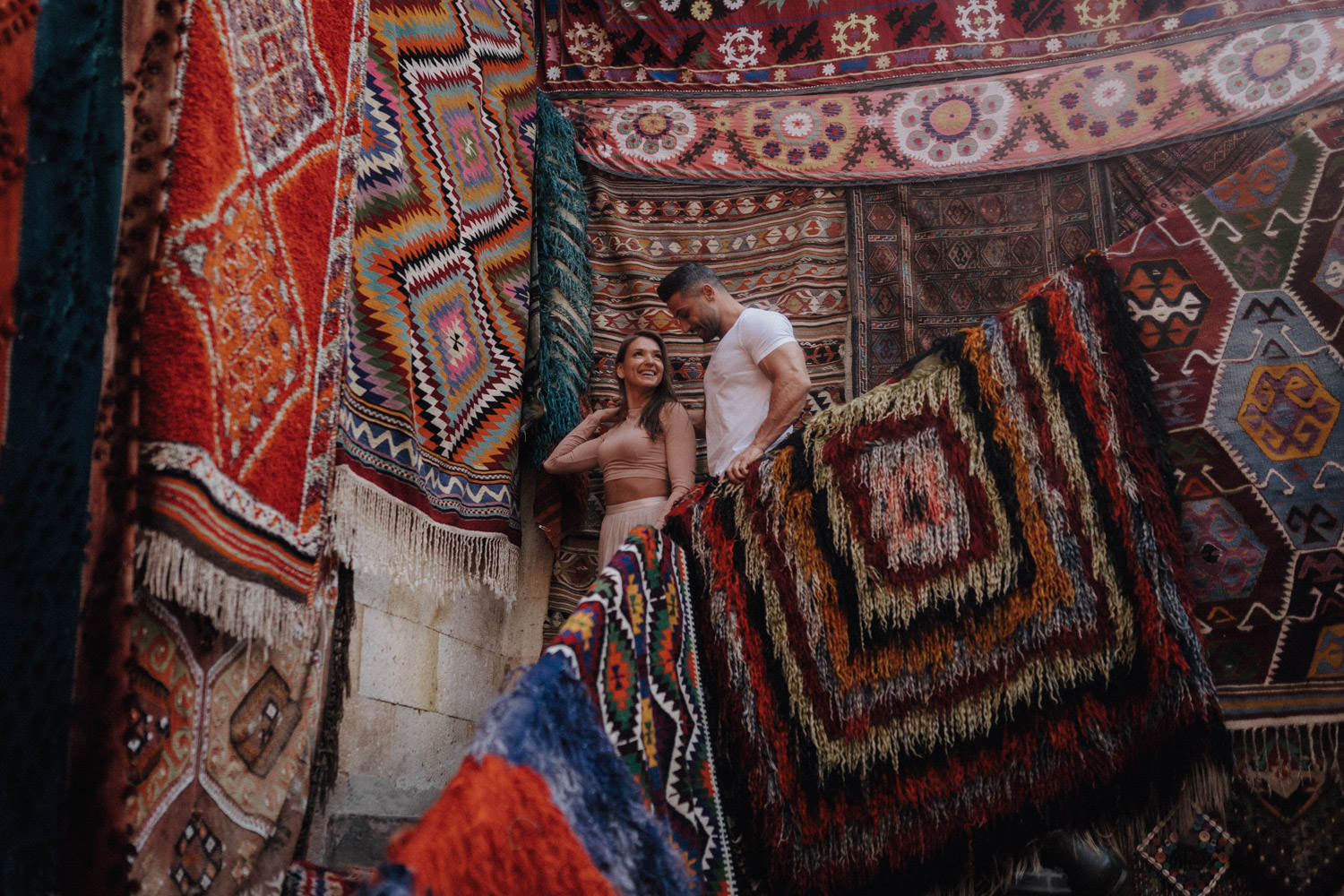 Ein in helle Farben gekleidetes Paar geht in einem türkischen Teppichladen in Kappadokien eine Treppe hinunter.