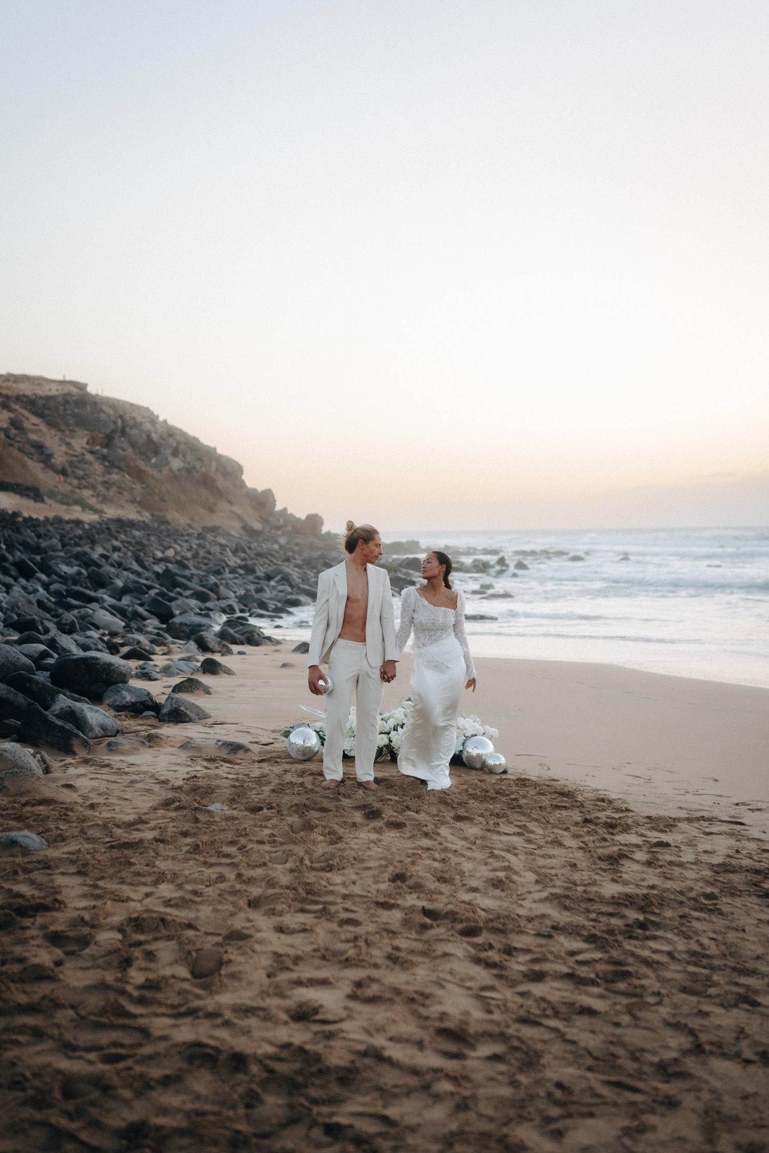 Ein Brautpaar im Disko-Stil posiert nach Sonnenuntergang am Strand von Fuerteventura.