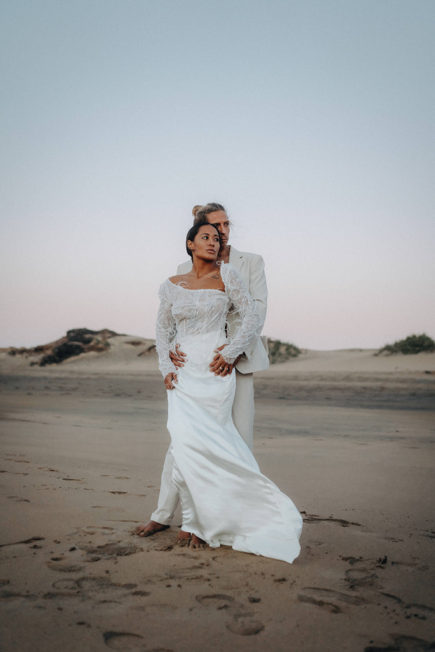 Ein Brautpaar steht in der Blue Hour am Strand von Fuerteventura und blickt gemeinsam auf das Meer hinaus.