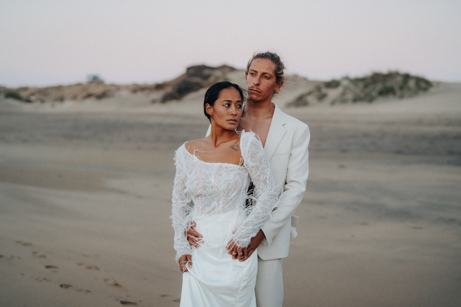 Ein Brautpaar steht in der Blue Hour am Strand von Fuerteventura und blickt gemeinsam auf das Meer hinaus.
