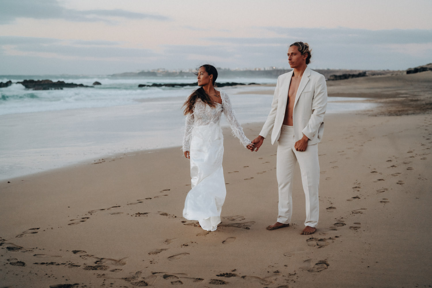 Ein Brautpaar im Disko-Hochzeitsstil steht Hand in Hand abends am Strand von Fuerteventura.