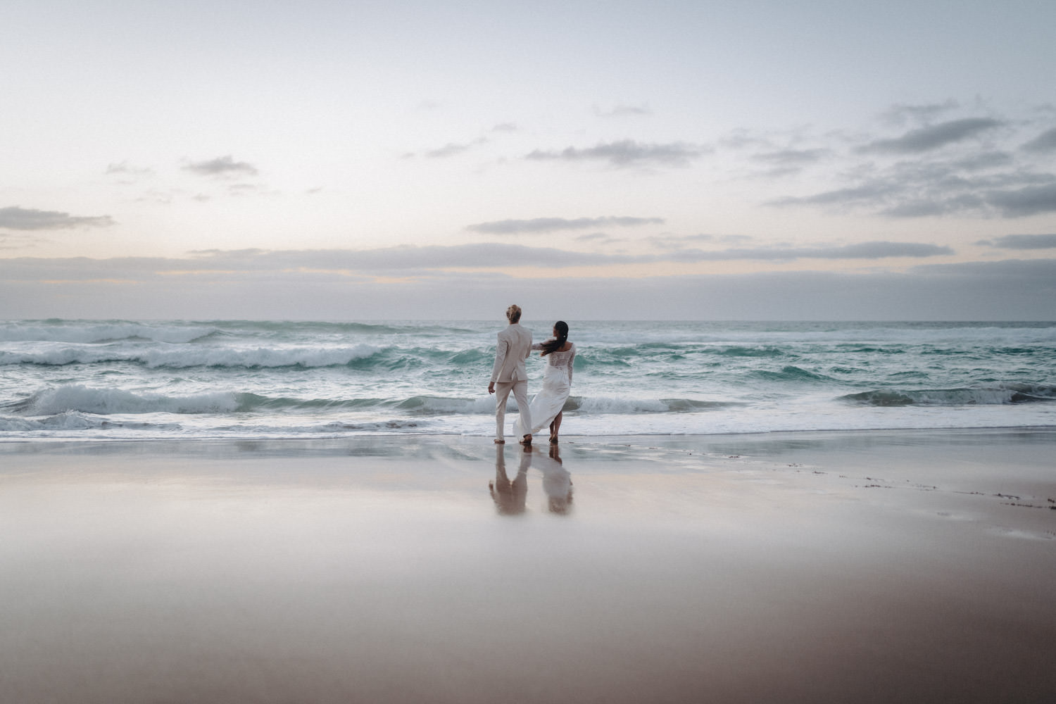 Ein Brautpaar im Disko-Hochzeitsstil steht am Abend am Meer.