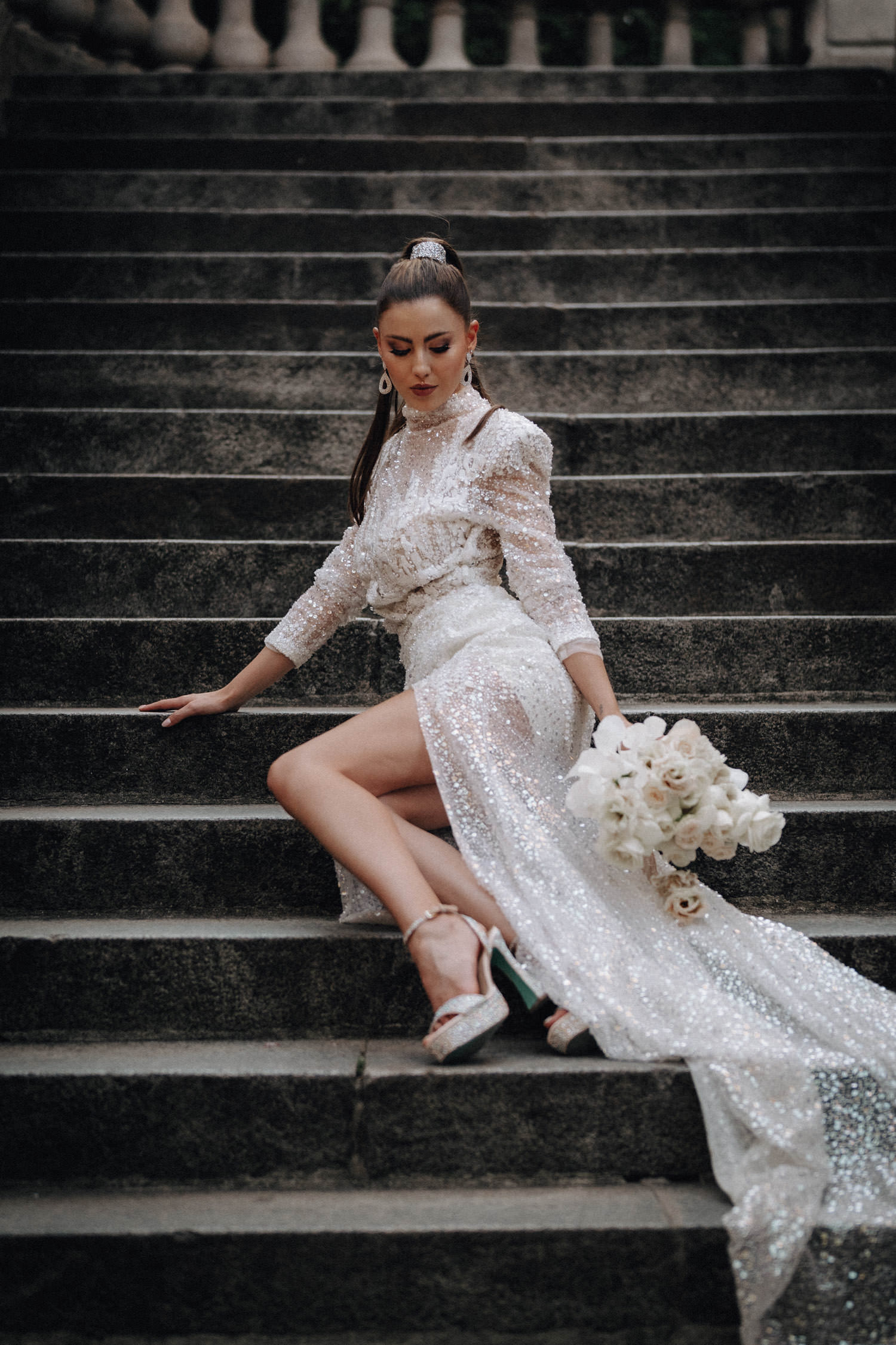 Eine Braut im Couture-Kleid sitzt auf Treppenstufen in Paris.