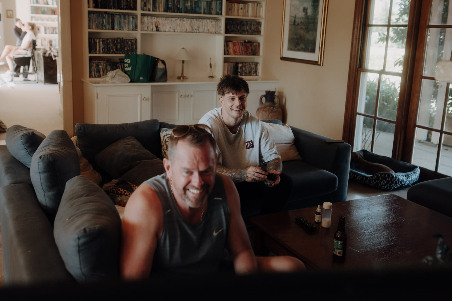Der Bräutigam und sein Schwiegervater sitzen auf der Couch und spielen Videospiele.