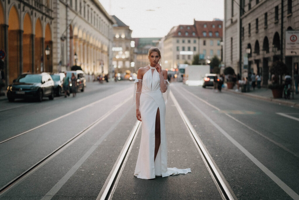 Ein Model im Brautkleid posiert auf Tramgleisen in der Altstadt von München.