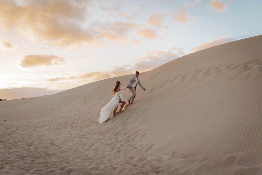 Ein Brautpaar läuft durch die Dünen von Fuerteventura.
