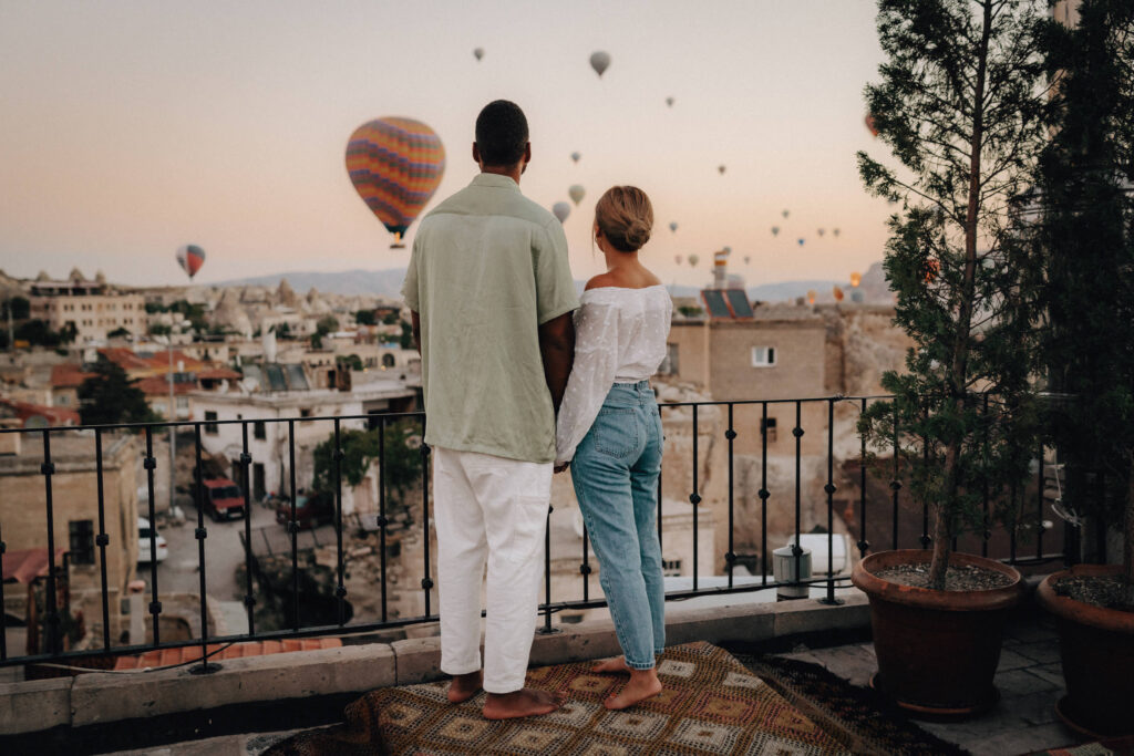 Ein Paar in lässigen Outfits genießt die Heißluftballons bei Sonnenaufgang in Kappadokien