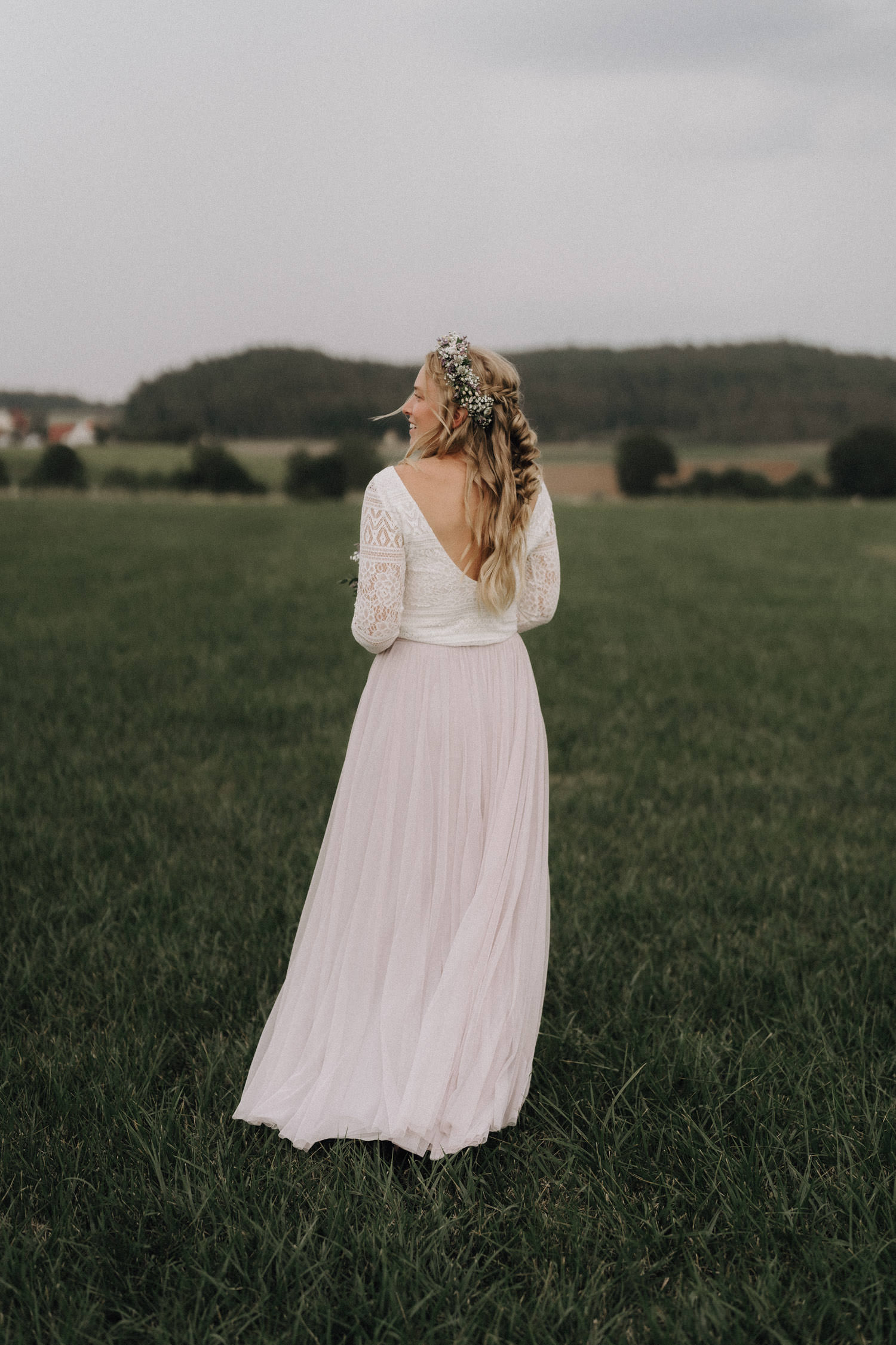 Eine Braut im Hippie Style steht auf einer Wiese